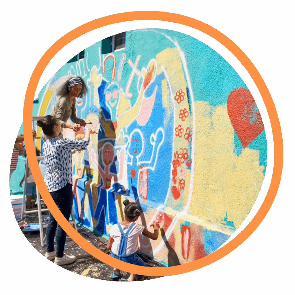 Adults and children painting a mural outdoors.